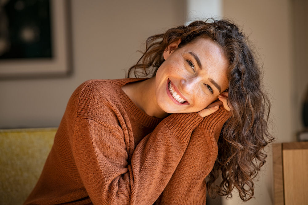 woman wearing brown sweater smiling and being happy