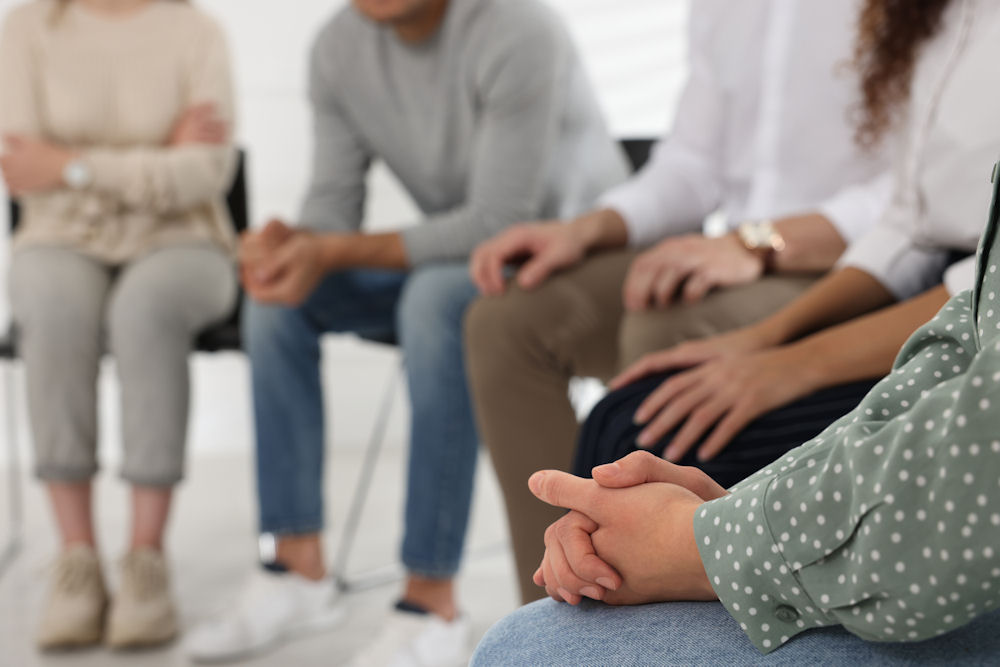 close up of hands in laps as group sits in circle for therapy