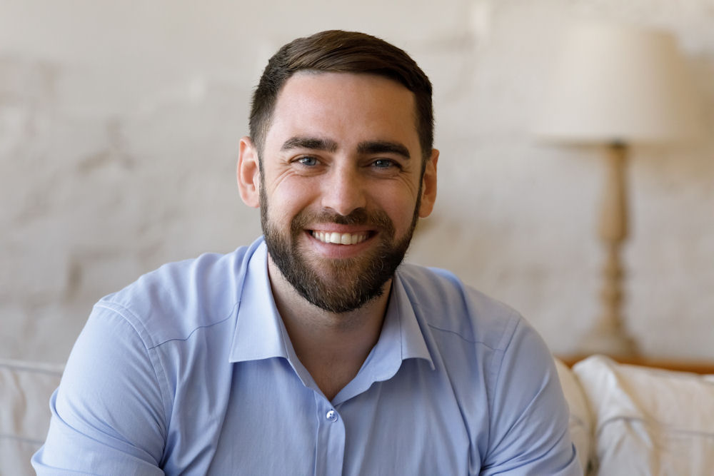 smiling man in light colored shirt looking at the camera