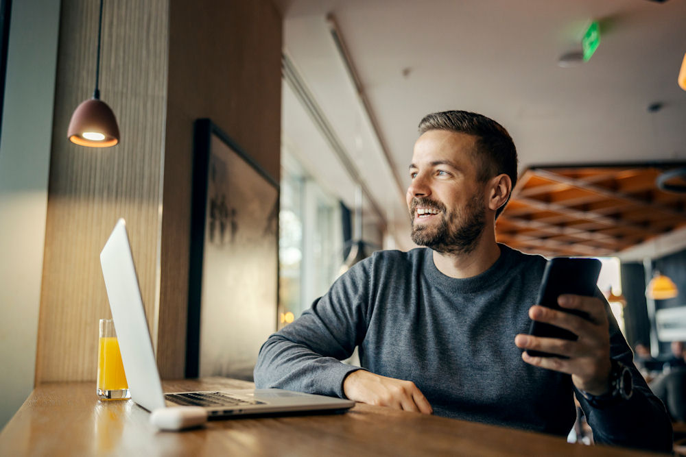 man sitting at a table with his laptop and phone